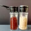 Set of 10 plastic pepper shakers, each with a 100ml capacity, featuring a perforated lid for easy dispensing.