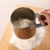 Stainless steel handheld flour sifter with double-layer fine mesh, ideal for baking and cooking.