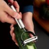 Stainless steel 2-in-1 peeler and shredder tool for peeling and shredding fruits, vegetables, and more.