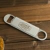 Custom metal beverage opener with personalized name engraving.
